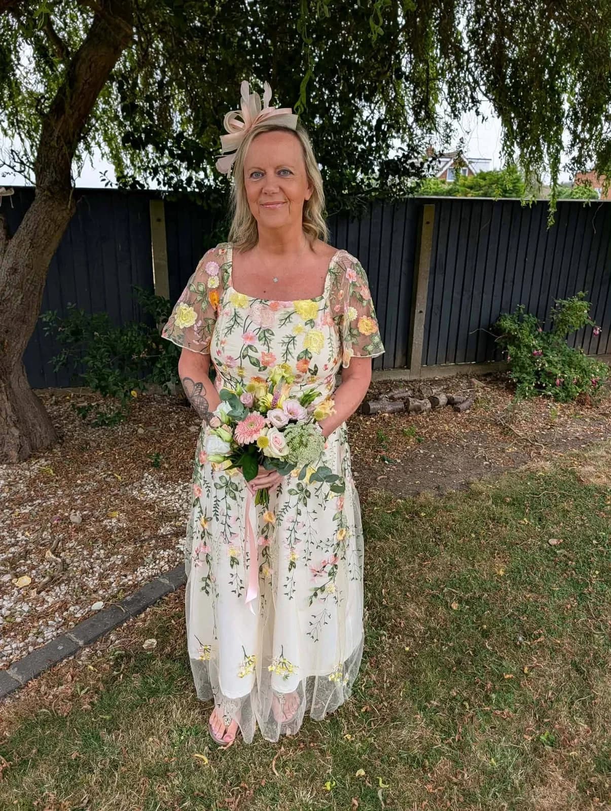 A bride holding a pastel pink, white and yellow bouquet