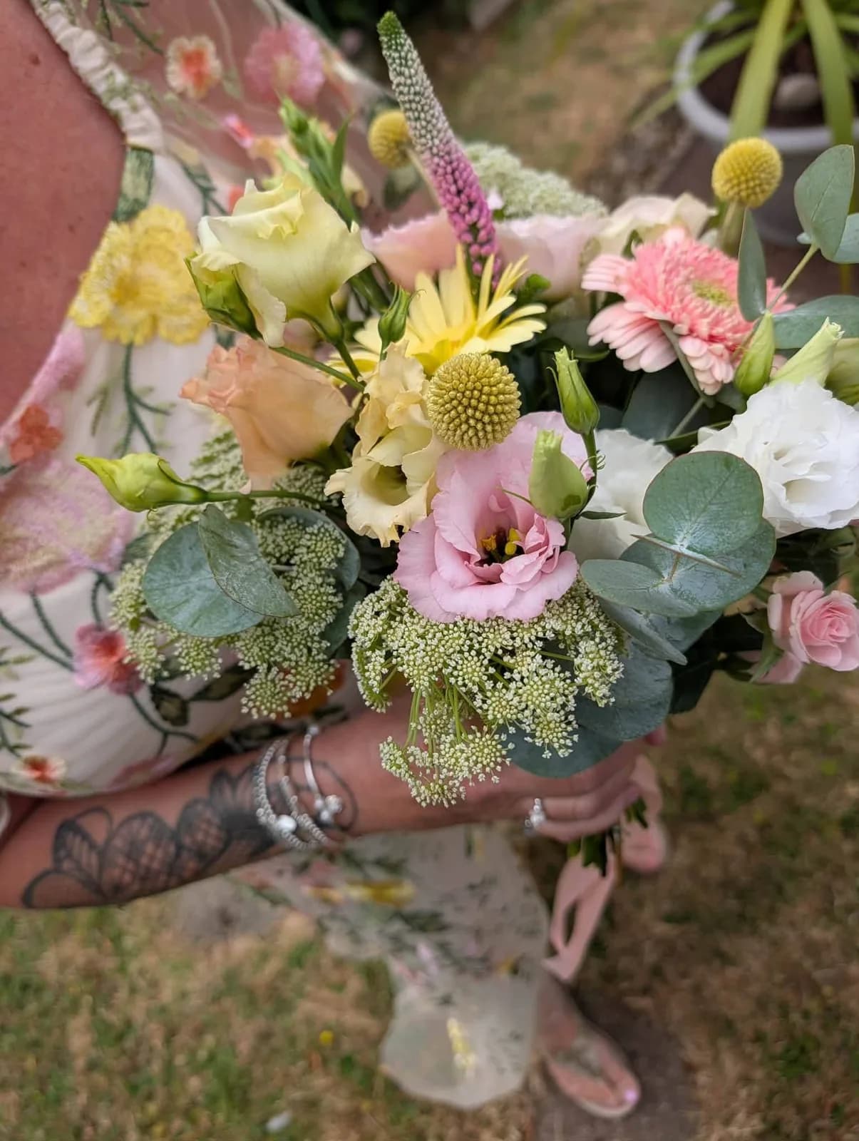 Pastel wedding flowers and the wedding rings held by the couple