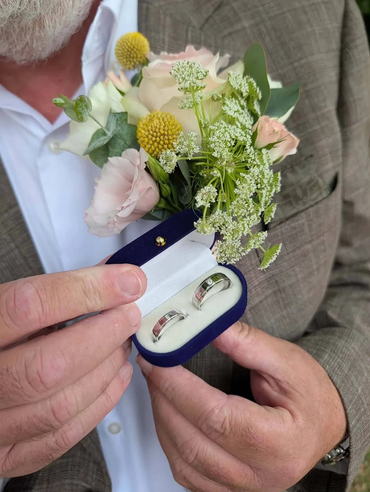A pastel pink rose buttonhole worn with a brown suit